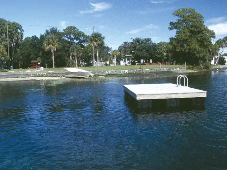 Swimming platform floating on the deep blue water of Hunter Spring in Crystal River, with palms and the park shoreline behind it