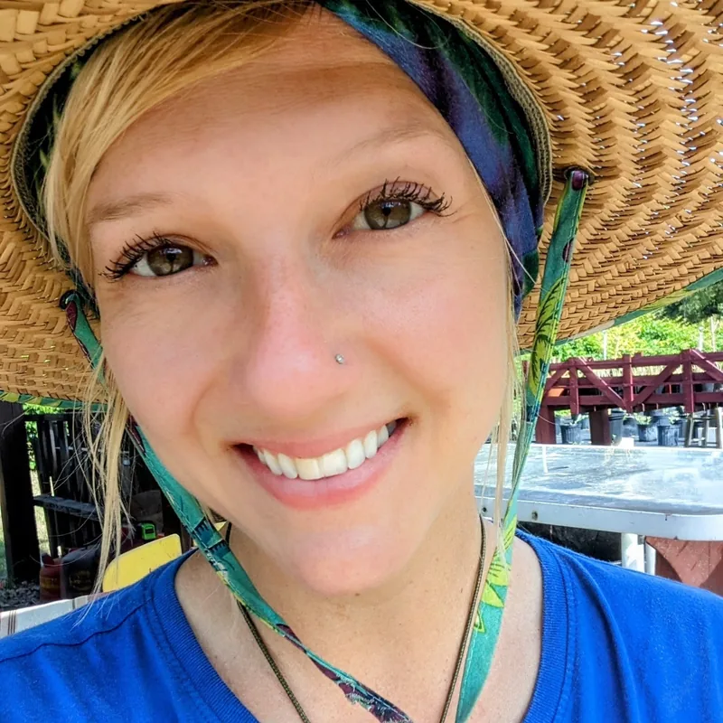 Laura, co-owner of Crystal River Orchard, smiling in a straw hat at the orchard